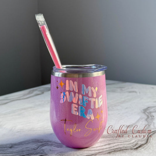 Pink tumbler with 'In My Swiftie Era' text and straw on a marble surface