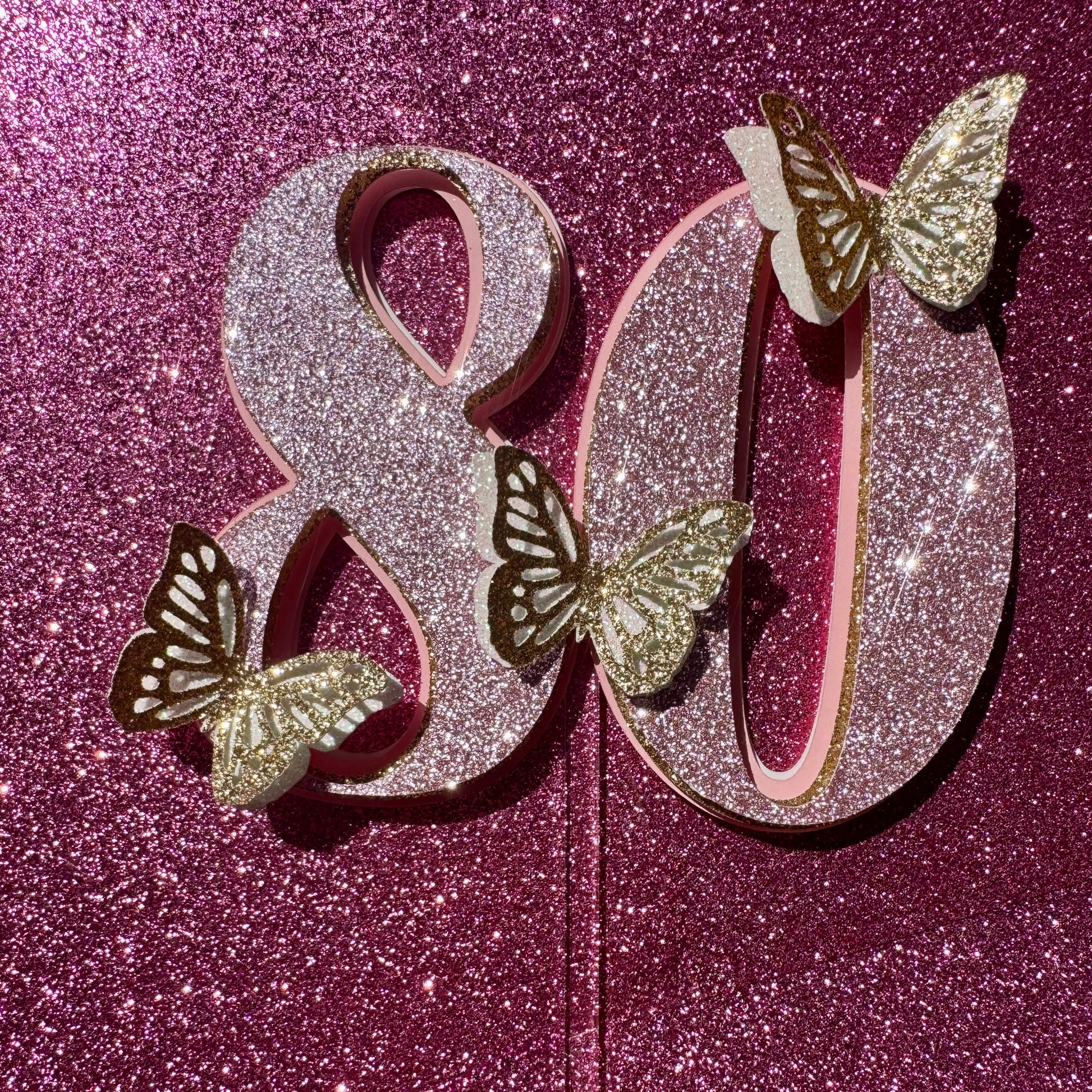 Decorative letters '80' with butterflies on a glittery pink background